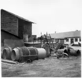 Vägstation Vmo X4, Bollnäs. Förrådsbyggnad med diverse skrot framför.