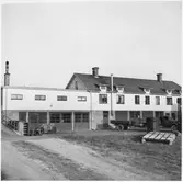 Vägstation Vmo X8, Ljusdal. Vinkelbyggt envånings bostadshus med tillbyggd garagelänga. Baksidan med garagebyggnad. Lastbil med släpkärra.