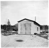Vägstation Y1, Ånge, filial Erikslund. Garagebyggnad, port på gaveln. Till vänster vägsladd och sidoplog.