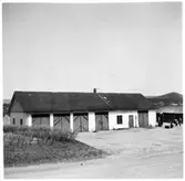 Vägstation Y2, Torpshammar. Garagebyggnad. Till höger bensinpumpar (drivmedelspumpar). Mansperson som fyller på drivmedel i bränslefat.