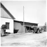 Vägstation Y2, Torpshammar. Garagebyggnad till vänster. Förrådsbyggnad. Traktor framför förrådsbyggnaden, cykelställ med cyklar.