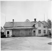 Vägstation Y3, Matfors, filial Njurunda. Byggnad med garage i mitten, bostäder (två våningar) till höger. Damcykel vid garageport.