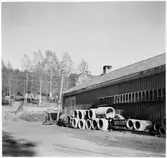 Vägstation Y4, Liden. Förrådsbyggnad (baksidan), upplag med diverse material, bland annat cementrör, underrede till decauvillevagn, sidoplog. Eventuellt oljegrusutläggare (bland cementrören).