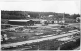 Vägstation Y6, Älandsbro. Vy över vägstationen med förrådsbyggnader, verkstad, kontor och garage. Upplag av trävirke med mera runt vägstationen.