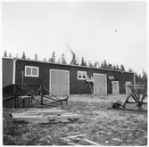 Vägstation Y8, Bjästa. Förrådsbyggnad. Vägmärken lutade mot byggnaden. Sidoplog, sidoplogfäste.