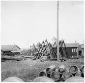 Y län. Före detta hamnförrådet. Förrådsbyggnader. Upplag av diverse material runt byggnaderna, bland annat sten- och stubbrytare, muffrör, cement- och betongblandare.