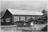 Vägstation Z6, Hede. Garage- och förrådsbyggnad. På garageplan spetsplogar. Lastbil med diverse last, bland annat trumma till grussorteringsverk.