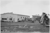 Vägstation Z11, Hammerdal. Förrådsbyggnader. I förgrunden vägsladd, till höger eventuellt grussorteringsverk. Mot väggen uppställda sandspridare.