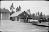 Vägstation AC1, Nordmaling. Förrådsbyggnad, garagebyggnaden skymtar till vänster. Bensinpumpar (drivmedelspumpar) varav en Ljungmans, modell Vici, bränsletank, (