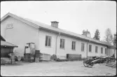 Vägstation AC1, Nordmaling. Vägstationens huvudbyggnad (baksidan) med verkstad, kontor och garage. Upplag av diverse material. Redskapslåda, cykelkärra.