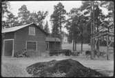 Vägstation AC3, Umeå. Förrådsbyggnader. Bostadshus i bakgrunden.