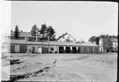 Vägstation AC14, Lycksele. Vägstationens huvudbyggnad, med från vänster verkstad, kontor, garage. Stenkross framför verkstaden. Garageplanen ännu ej färdigplanerad. Bostadshus i bakgrunden.
