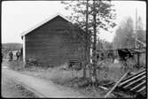 Vägstation AC13, Malåträsk. Garagebyggnad (baksidan). Personbil och manspersoner vid byggnaden.