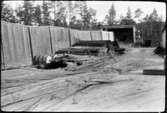 Depåförråd VFAC (Vmo AC5, Vindeln). Förrådsbyggnad, öppet skjul. Framför byggnaden diverse materiel, eventuellt armeringsjärn.