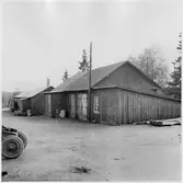 Vägstation BD9, Haparanda. Förrådsbyggnader. Upplag av diverse materiel. Väghyvel skymtar till vänster. Cykel vid byggnaden.