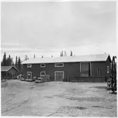 Vägstation BD11, Pajala. Förrådsbyggnad i två våningar, med lastkaj. Upplag av bränslefat utanför byggnaden.