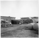 Kvarteret Stören, Luleå. Förrådsbyggnader. Upplag av diverse materiel, bland annat rör och ved.