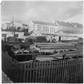 Kvarteret Stören, Luleå. Förrådsbyggnader. Upplag av diverse materiel. I bakgrunden bostadshus, bland bostadshuset (till vänster) Bostadsrättsföreningen Sillen, uppförd 1939.