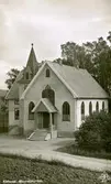 Vykort på Kållereds Missionskyrka (senare Ekenkyrkan) cirka 1940 - 1950. Missionskyrkan byggdes 1923-24 och ersatte då ett äldre missionshus från 1880-talet. Idag är Ekenkyrkan, tillsammans med Centrumkyrkan, en del av Equmeniaförsamlingen i Kållered. Relaterat motiv: A1002.