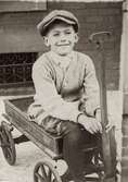 Robert Nelson 8 ½ år (född 1908) sitter på en skrinda i Philadelphia, USA år 1916. Son till Carl Nelson (född i Sverige, död i USA) och Alma Nelson (född 1881 i Kållered - död 1959 i USA). Hennes far var Karl Eriksson från Vommedal Östergård 