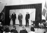 Fyra män uppträder på en scen under Stenmans verkstadsklubbs tjugofem-årsjubileum 1939-1964 på Folkets Hus i Alingsås.