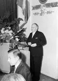 Stenmans verkstadsklubb tjugofem-årsjubileum 1939-1964 på Folkets Hus i Alingsås. Vid talarstolen står Fritz Mühlheim, VD för Assa Stenman i Alingsås.