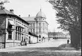 Åsbogatan från Allégatan med gamla lasarettsbyggnaden i fonden  och Sparbanken t.v. i kvarteret Vale. 1880-talet.
