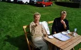 Hembygdsdag vid Hembygdsgården Långåker 1:3, 1990-tal. Elisabet Pettersson till vänster och en okänd kvinna sitter och fikar i trädgårdsmöblerna. Parkerade bilar ses i bakgrunden.