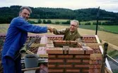 Sista varvet av tegel för Hembygdsgården Långåker 1:3, 19 augusti 1994. Berny Gustafsson (till vänster) tar muraren Henry Nilsson, Sandbäck, i hand. Hans sista arbete var bakugnen på Långåker.