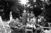 Några kvinnor och män fikar i det gröna.

Stående från vänster: Alfhild Friskopp, Elsa Kihlman, Ingrid Vidlund.
Sittandes från vänster: Paul Kopp, Olof Brunzell, Vilhelm Friskopp, fru Nilsson med maken Einar Nilsson, okänd man.