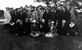 Bilden visar ett 50-tal kvinnor och män samt ett barn som står och sitter framför en sjö.
Troligen en frikyrklig grupp på Torstö, Mjörn.