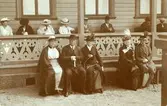 Ett antal personer sitter utanför ett hus på en veranda.