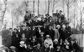 En större grupp människor, både män och kvinnor, uppställda för fotografering. Eventuellt är bilden tagen i Folkets park.