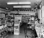 Konsumbutik på Viktoriagatan. Hyllor med diverse produkter. Överst på bakre väggen texten 