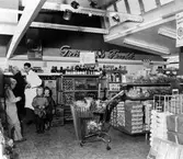 Konsumbutiken på Sjömansvägen i Stockslycke. Tre pojkar och en kvinna vid avdelningen för bröd och läsk.