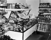 Butiksinteriör från Konsum, troligen Norra Strömgatan. Hyllor med konsever och en kyldisk med diverse livsmedelsprodukter.