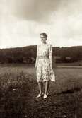 Ingrid Andersson (1918 - 2001, gift Skansing) står på en grusväg cirka 1940. Gården Livered 