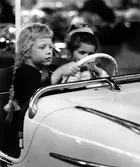 Barnens dag 1960. Två flickor sitter i en karusellvagn.