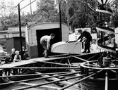Barnens dag 1960, Lilla torget. Två män monterar en karusell medan några barn tittar på.