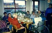 Fikastund i Brattåsgårdens matsal, 1980-tal. Närmast fönstret, från vänster (på vänster sida): 1. Svea, Mölndal. 2. Sonja Gustavsson, Hallebo Lindome. 3. Aina Söderqvist, Bölet Kållered. 
Närmast fönstret, från vänster (på höger sida): 4. Majken, Lindome. 5. Gunvor Johansson (i ljusblå blus). 6. Okänd man. 7. Elin Jansson, Kållered (i rullstol). Stående till höger: Margit Antonsson, Kållered.