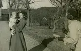 Mary Ekman (1920 - 1988) håller sonen Ulf-Göran (född 1942) i famnen, år 1942. De står på uppfarten till 