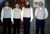 Invigning av mansvästen, gemensam för Kållered och Mölndals Hembygdsföreningar, i Fässbergs församlingshem, 1990-tal. Originalet (se A2910) kommer ifrån Alegårdsslätt i Fässberg. Från vänster: 1. Okänd man, 2. Tage Bernhardsson, 3. Lars Gahrn, 4. Anton Johansson. Relaterat motiv: A2909.