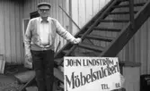 John Lindström (född 1902 i Lindome, död 1989 i Kållered) står utanför sitt snickeri på Gamla Riksvägen 79 (nu: Gamla Riksvägen 81), 1980-tal. På skylten står det 