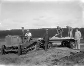 Arbetare med traktor och släp.