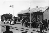 Invigning av Ätrans nya stationshus och Varberg-Ätrans Järnväg 1911-07-22. En stor folkskara har samlats för festligheterna. Till vänster syns den äldre stationsbyggnaden som hört till Fegen-Ätrans Järnväg invigd 1887. Villkoret för att Varberg-Ätrans Järnväg skulle få ansluta till den befintliga stationen var att man förutom nytt stationshus även uppförde ett nytt godsmagasin och bekostade banområdets utvidgning. Fram tills dess hade järnvägen från Fegen slutat här med Ätran som s k säckstation.