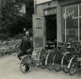 Gösta Olsson (1920 - 1989) i sin cykel- och mopedverkstad (eventuellt även radioapparater) i sin lokal 