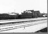 Varbergs järnvägsstation en vinterdag. Bilden tagen mot sydost från spårsidan. Ett tåg står inne.