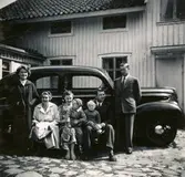 Sju personer står samlade framför en bil vid Ekans gård, Ekan 1:1, år 1953. Från vänster: 1. Eva Svensson (född 1936, gift Johansson, dotter till nr 7). 2. Elsa Svensson (1901 - 1990, gift med nr 7), gårdens ägare. 3. Edit Melin (1918 - 2000), Kyrkbacken. 4. sonen Lars-Åke Melin (född 1948), Kyrkbacken. 5. sonen Sven-Olof Melin (född 1951), Kyrkbacken. 6. Åke Melin (1913 - 1970), Kyrkbacken. 7. Rolf Svensson (född i Släp 1909, avliden i Kållered 1989), gårdens ägare och brukare.