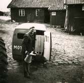 Gårdsplanen vid Ekans gård, Ekan 1:1, år 1953. Traktorreparatören Malte med en cigarett i munnen och en oljekanna i handen. Relaterat motiv: A1147.