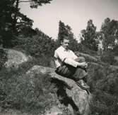 Rolf Svensson (1909 - 1989), iförd basker, sitter på en stenbumling vid Ekans gård, Ekan 1:1, år 1953. Han ägde och brukade gården.